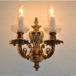 Golden wall light with two metal arms made of solid cast brass.