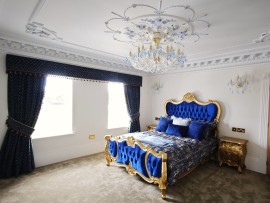 The 18-bulb version of the chandelier matches the blue double bed in the bedroom.