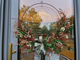Entrance door to the gazebo with a chandelier. The door with autumn decorations is complemented by the glow of the chandelier.