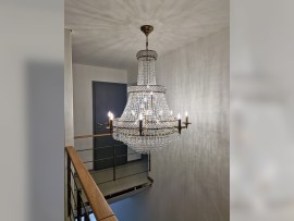 The chandelier fits into a minimalist interior with wood on the railing